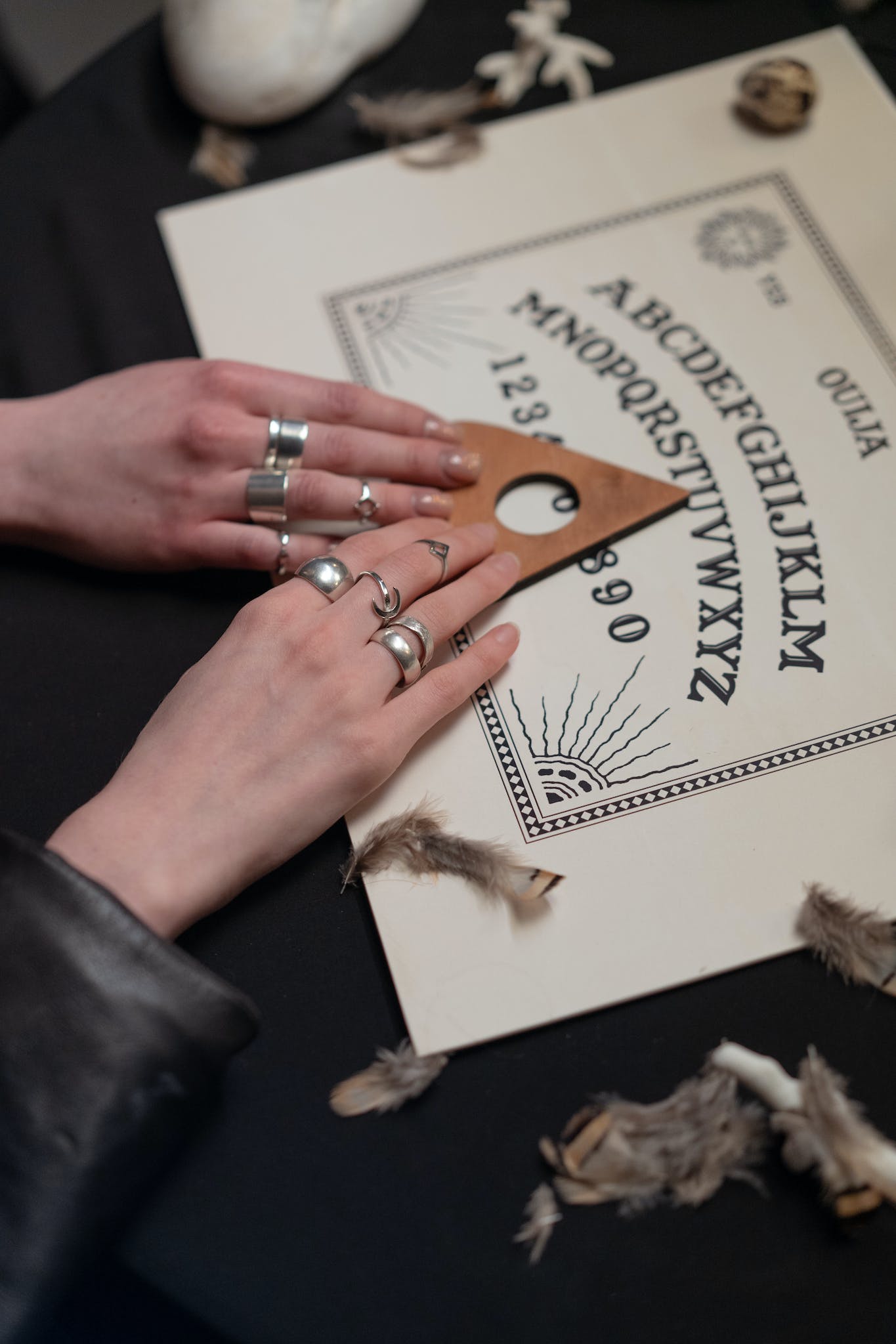 Hands of Women Holding an Arrow on a Ouija Board